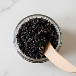 Exfoliating Sugar Coffee Scrub in glass jar sits on white marble countertop
