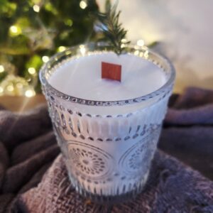 Winter Wonderland-Vintage Glass White Soy Candle with Cedar Wick sits in front of a blurred lit tree.