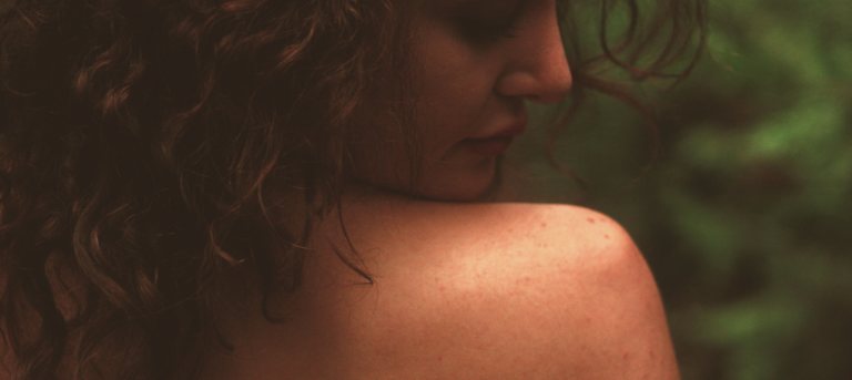 Side profile of woman with curly hair looking at shoulder